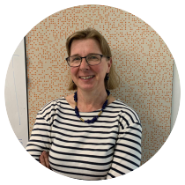 A/P Alice Richardson wears a striped shirt, dark framed glasses, chunky necklace and a smile on her face